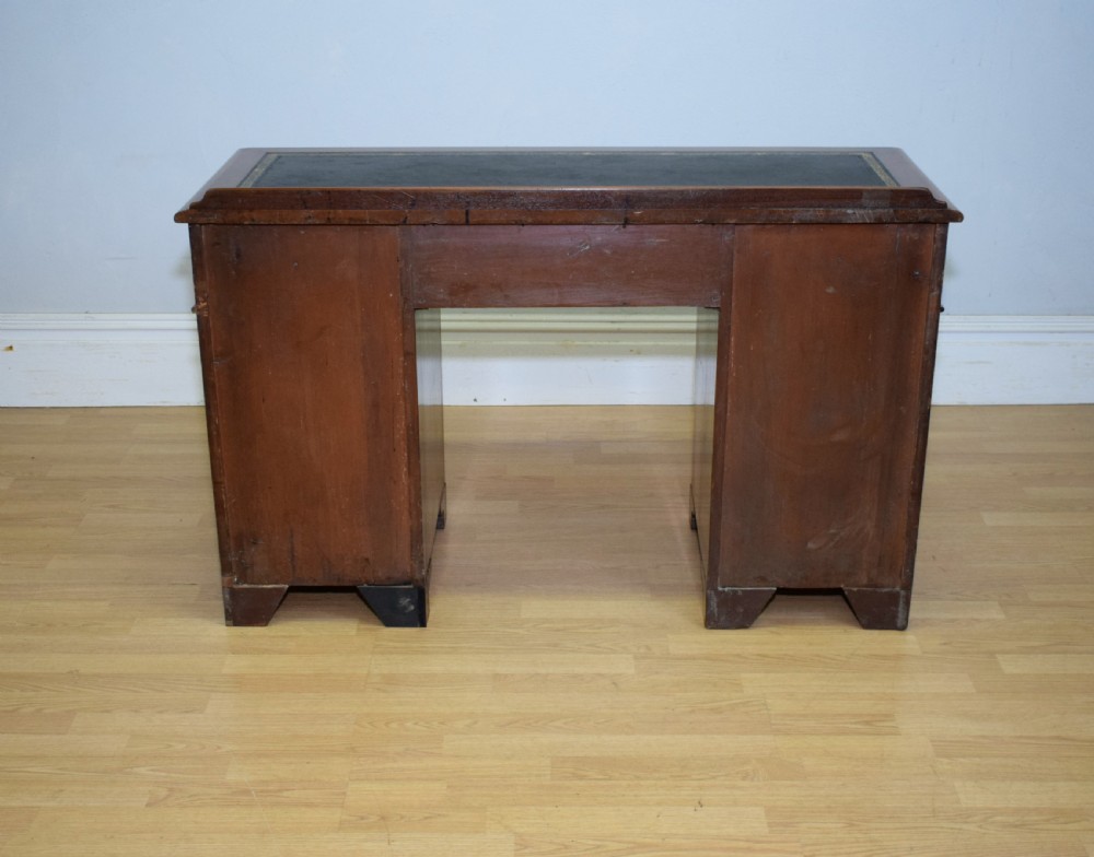 A Victorian mahogany pedestal desk featuring a dark green leather inset writing surface, three frieze drawers, and arched panel pedestal doors. View XXII