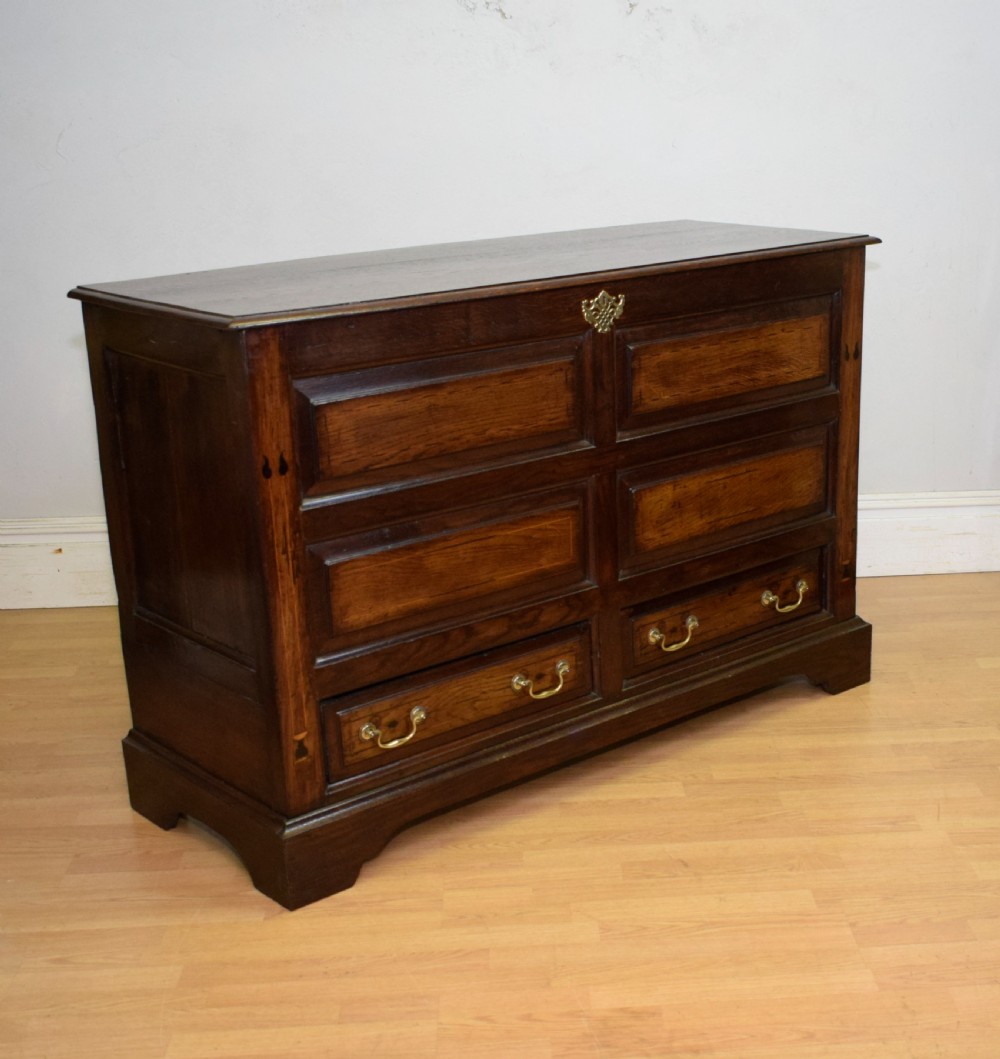 A Georgian dark oak Lancashire mule chest featuring a hinged top lid, panelled front sections with inlays, brass swan-neck handles, and bracket feet. View III
