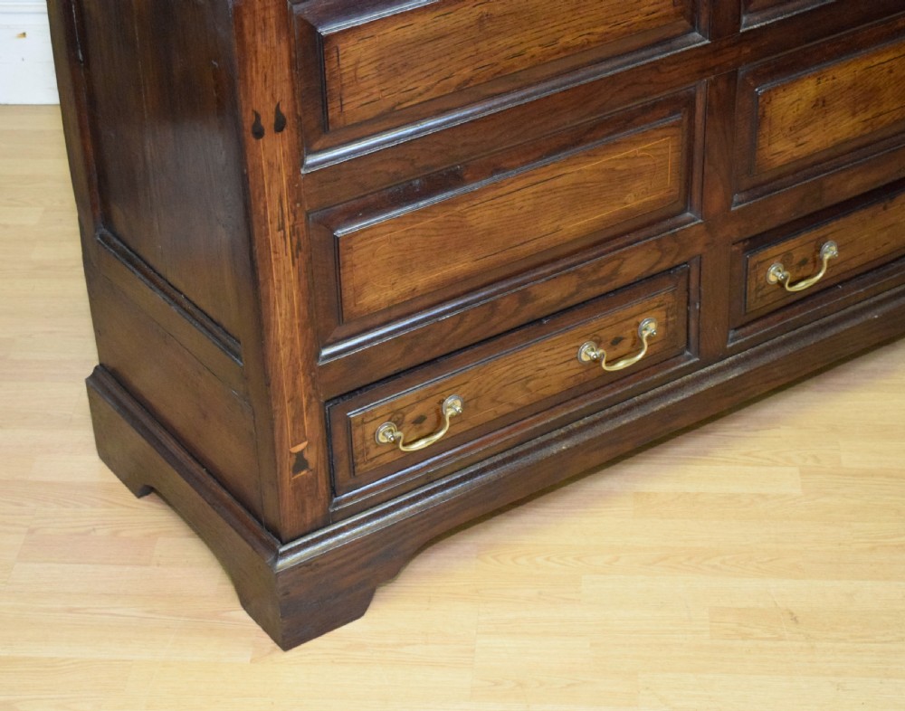 A Georgian dark oak Lancashire mule chest featuring a hinged top lid, panelled front sections with inlays, brass swan-neck handles, and bracket feet. View VII
