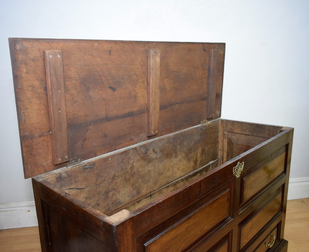 A Georgian dark oak Lancashire mule chest featuring a hinged top lid, panelled front sections with inlays, brass swan-neck handles, and bracket feet. View VIII