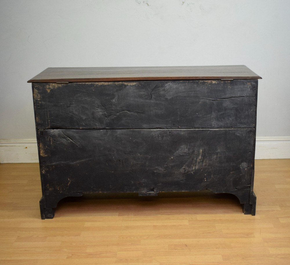 A Georgian dark oak Lancashire mule chest featuring a hinged top lid, panelled front sections with inlays, brass swan-neck handles, and bracket feet. View XII