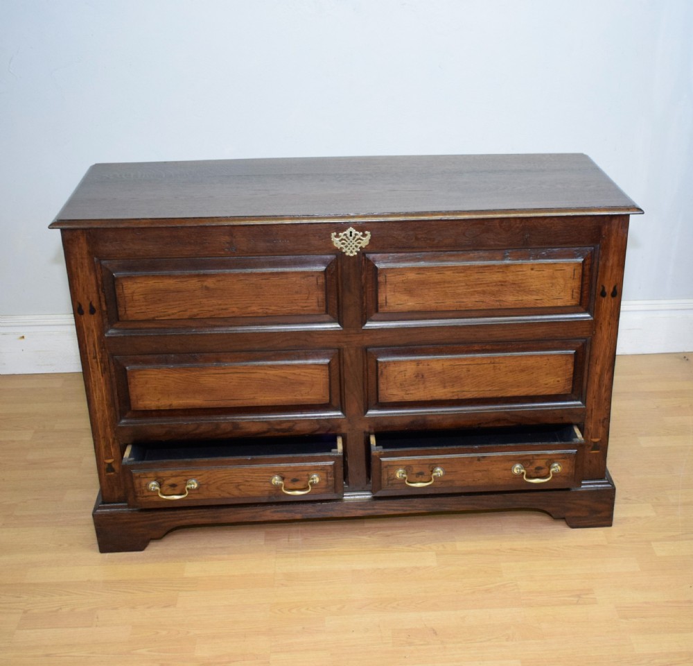 A Georgian dark oak Lancashire mule chest featuring a hinged top lid, panelled front sections with inlays, brass swan-neck handles, and bracket feet. View XVI