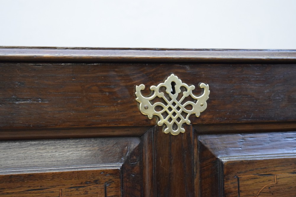 A Georgian dark oak Lancashire mule chest featuring a hinged top lid, panelled front sections with inlays, brass swan-neck handles, and bracket feet. View XVII