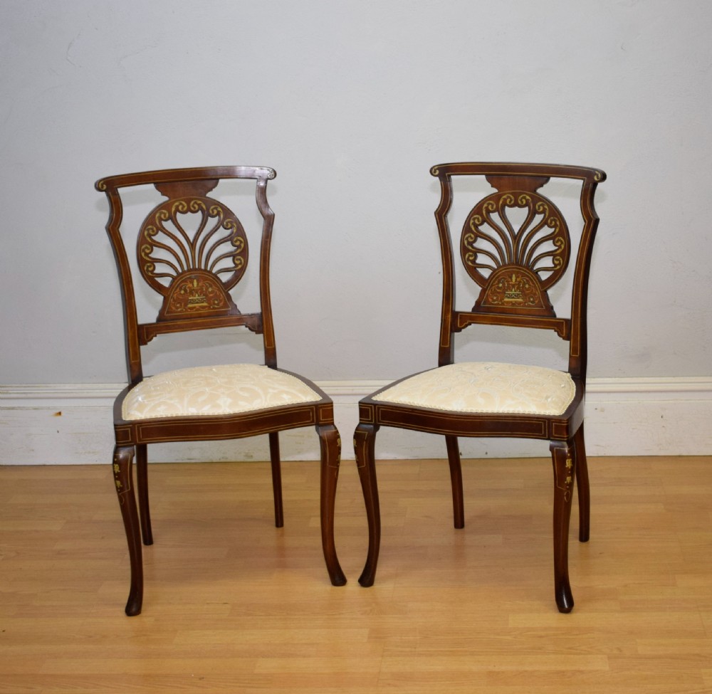 A pair of Victorian side chairs featuring dark mahogany frames with detailed marquetry inlays, fan-shaped pierced backrests, and cream upholstered seats. View V