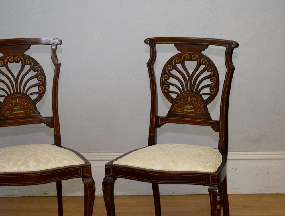 A pair of Victorian side chairs featuring dark mahogany frames with detailed marquetry inlays, fan-shaped pierced backrests, and cream upholstered seats. View VI