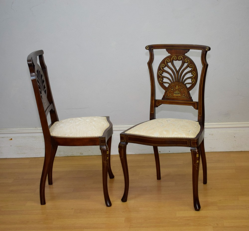 A pair of Victorian side chairs featuring dark mahogany frames with detailed marquetry inlays, fan-shaped pierced backrests, and cream upholstered seats. View XIX