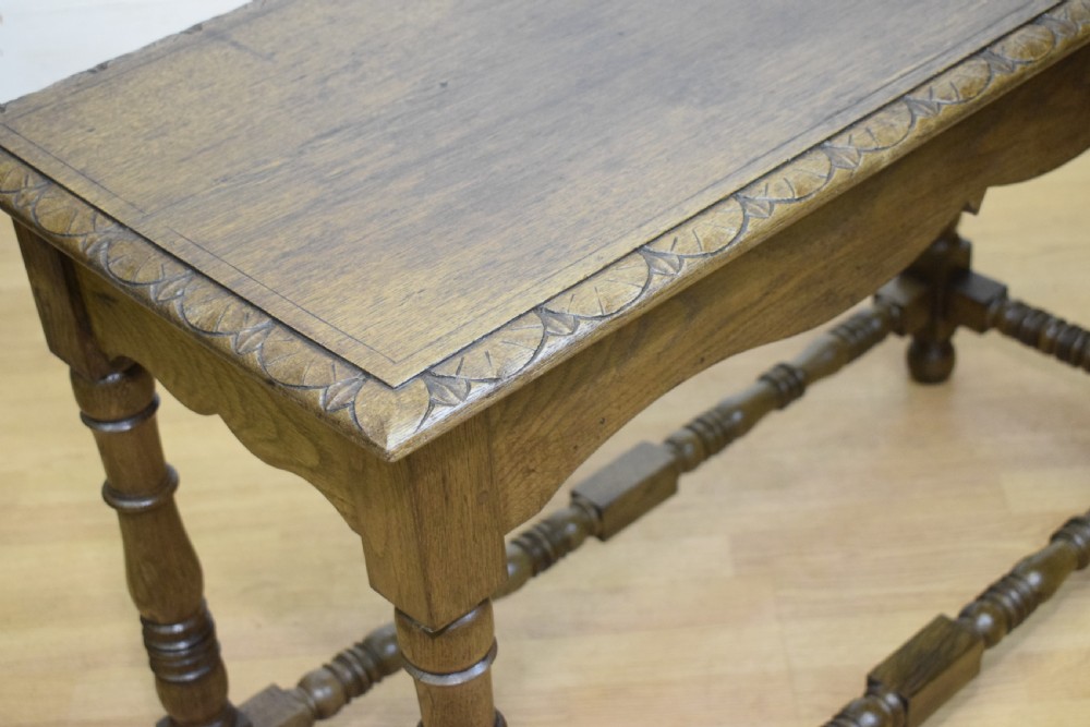 An early 20th-century oak console table featuring turned legs, a shaped apron, carved top edge, and low stretcher supports. View V