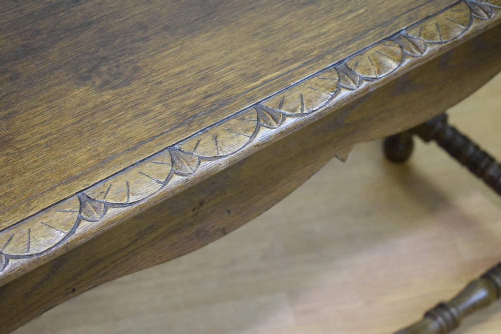 An early 20th-century oak console table featuring turned legs, a shaped apron, carved top edge, and low stretcher supports. View VII