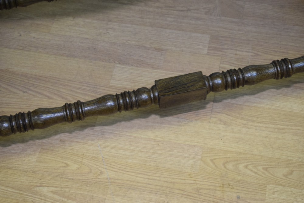 An early 20th-century oak console table featuring turned legs, a shaped apron, carved top edge, and low stretcher supports. View X