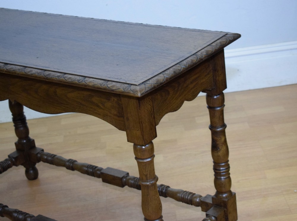An early 20th-century oak console table featuring turned legs, a shaped apron, carved top edge, and low stretcher supports. View XI