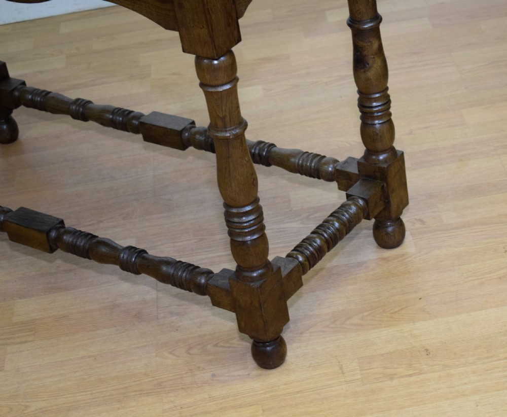 An early 20th-century oak console table featuring turned legs, a shaped apron, carved top edge, and low stretcher supports. View XII