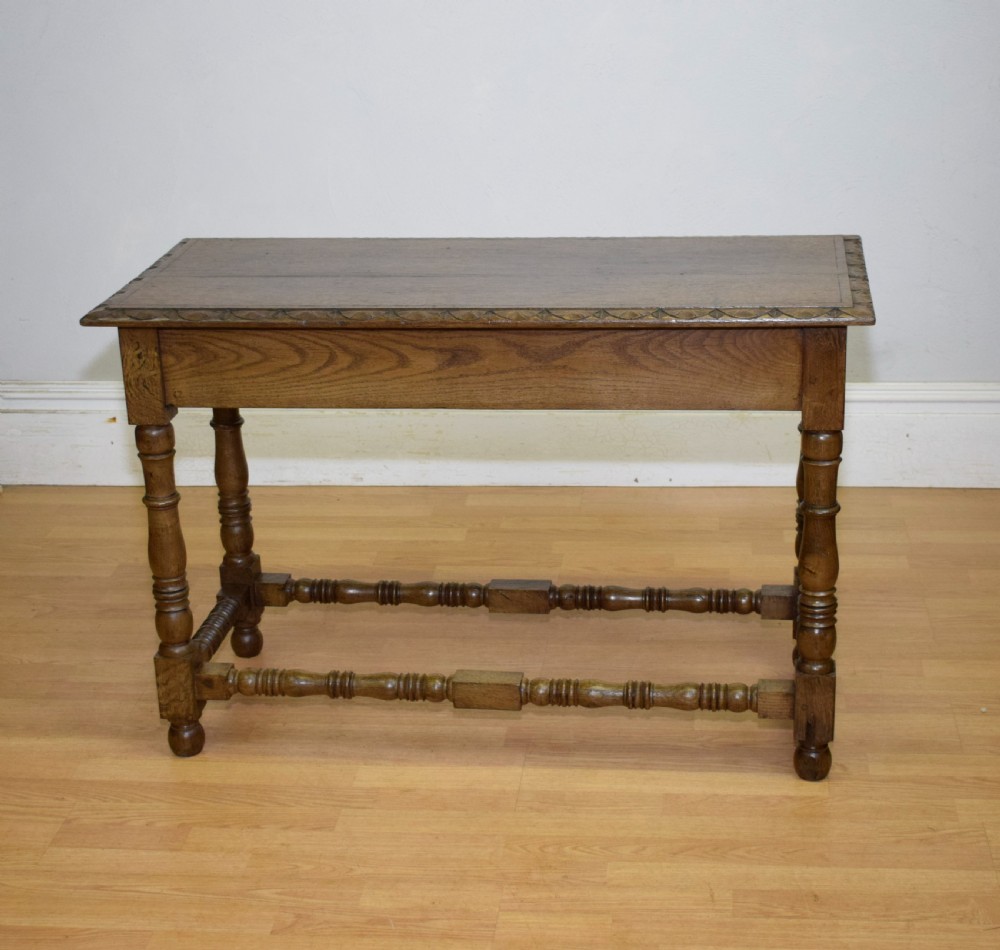 An early 20th-century oak console table featuring turned legs, a shaped apron, carved top edge, and low stretcher supports. View XVI
