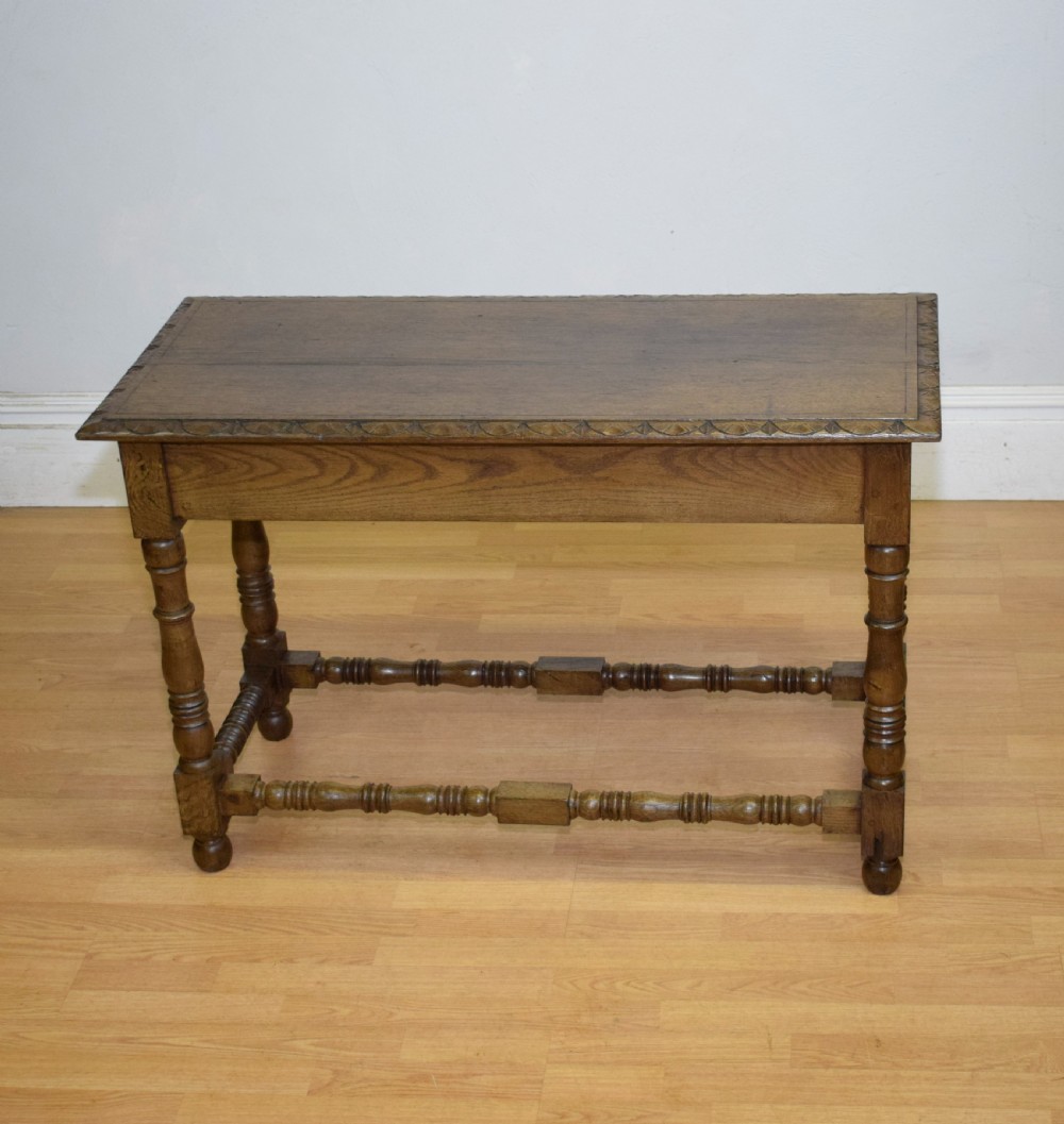 An early 20th-century oak console table featuring turned legs, a shaped apron, carved top edge, and low stretcher supports. View XVII
