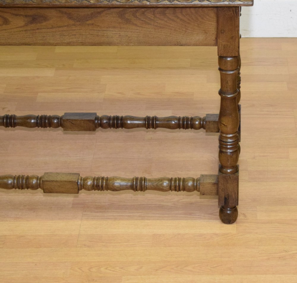 An early 20th-century oak console table featuring turned legs, a shaped apron, carved top edge, and low stretcher supports. View XVIII