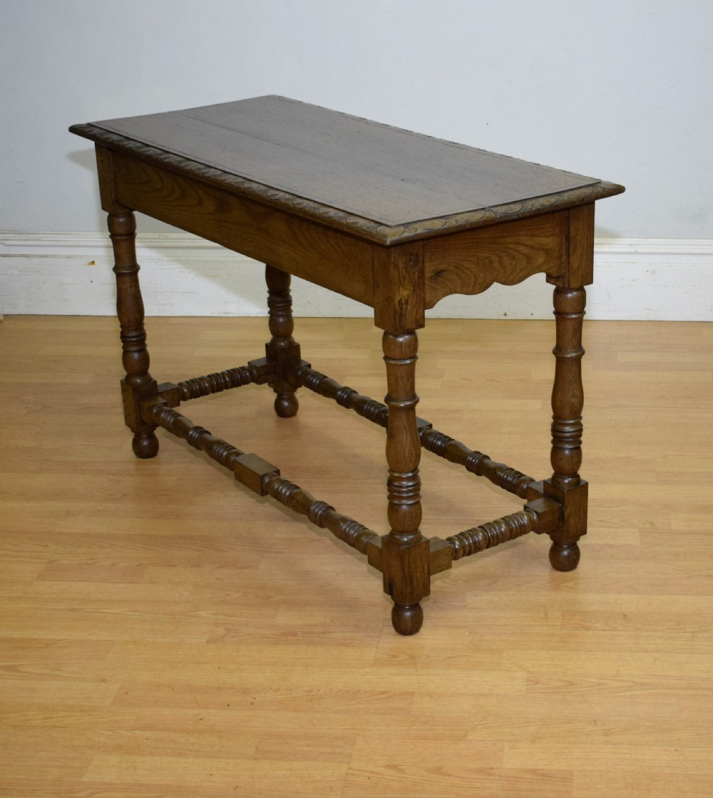 An early 20th-century oak console table featuring turned legs, a shaped apron, carved top edge, and low stretcher supports. View XIX