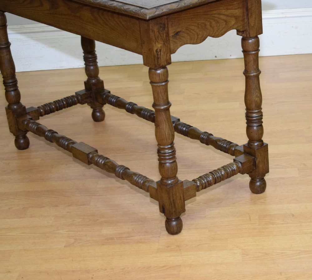 An early 20th-century oak console table featuring turned legs, a shaped apron, carved top edge, and low stretcher supports. View XX