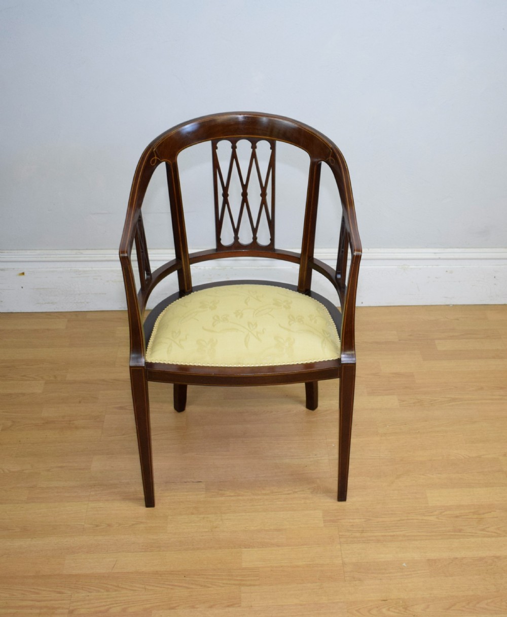 An Edwardian dark mahogany tub armchair featuring boxwood stringing inlay, pierced lattice back panels, and a yellow patterned upholstered seat. View III
