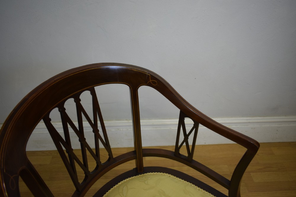 An Edwardian dark mahogany tub armchair featuring boxwood stringing inlay, pierced lattice back panels, and a yellow patterned upholstered seat. View VIII