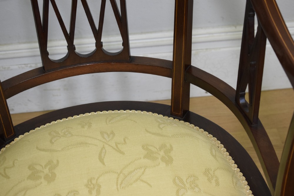 An Edwardian dark mahogany tub armchair featuring boxwood stringing inlay, pierced lattice back panels, and a yellow patterned upholstered seat. View XVI