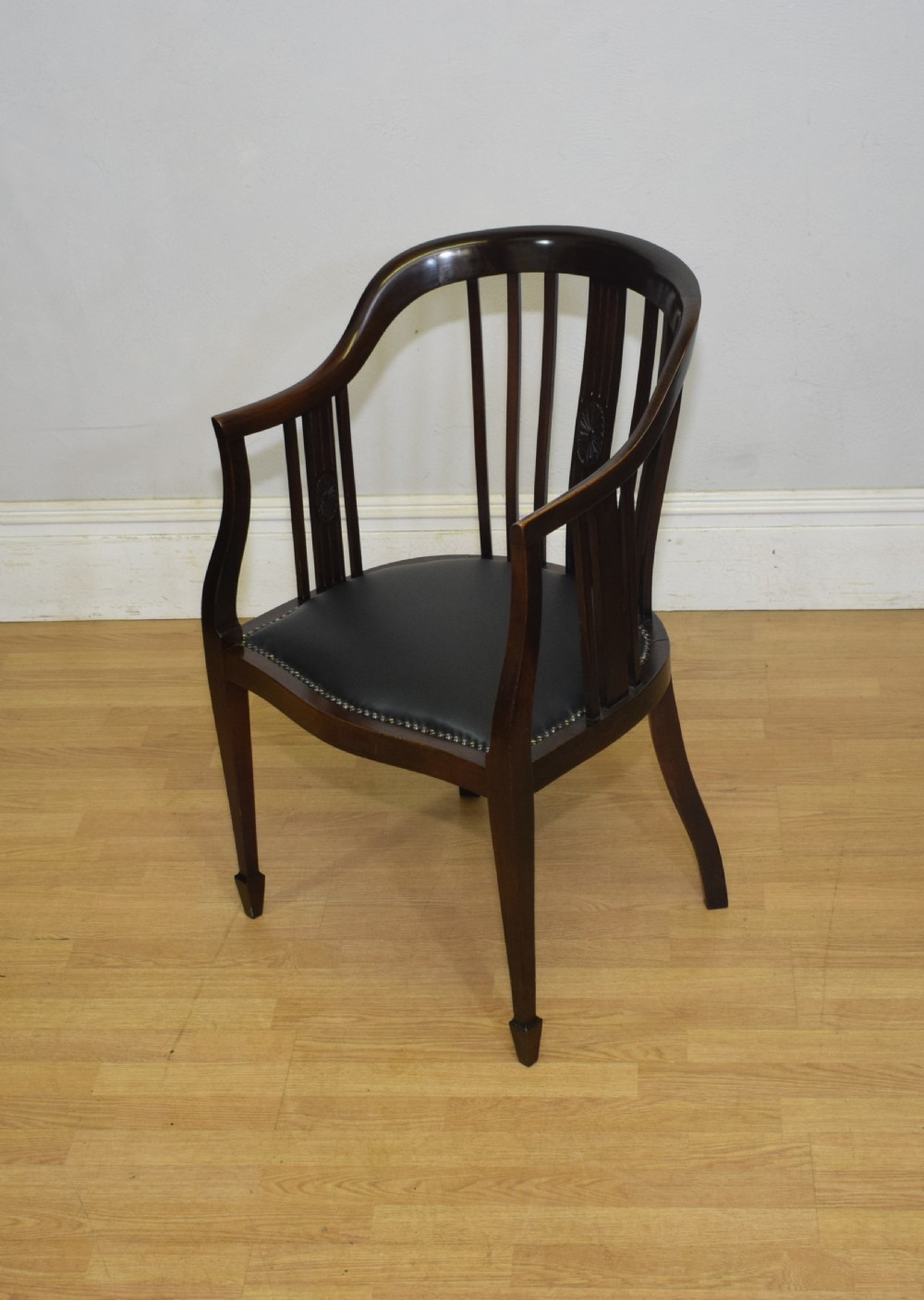 A Victorian dark mahogany tub chair featuring a curved backrest with vertical splats, a central carved oval patera, and a black leather studded seat. View IV