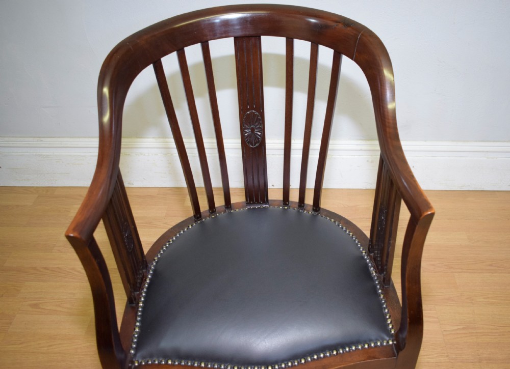A Victorian dark mahogany tub chair featuring a curved backrest with vertical splats, a central carved oval patera, and a black leather studded seat. View IX