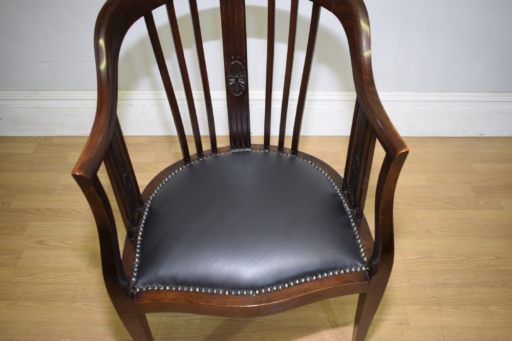 A Victorian dark mahogany tub chair featuring a curved backrest with vertical splats, a central carved oval patera, and a black leather studded seat. View X