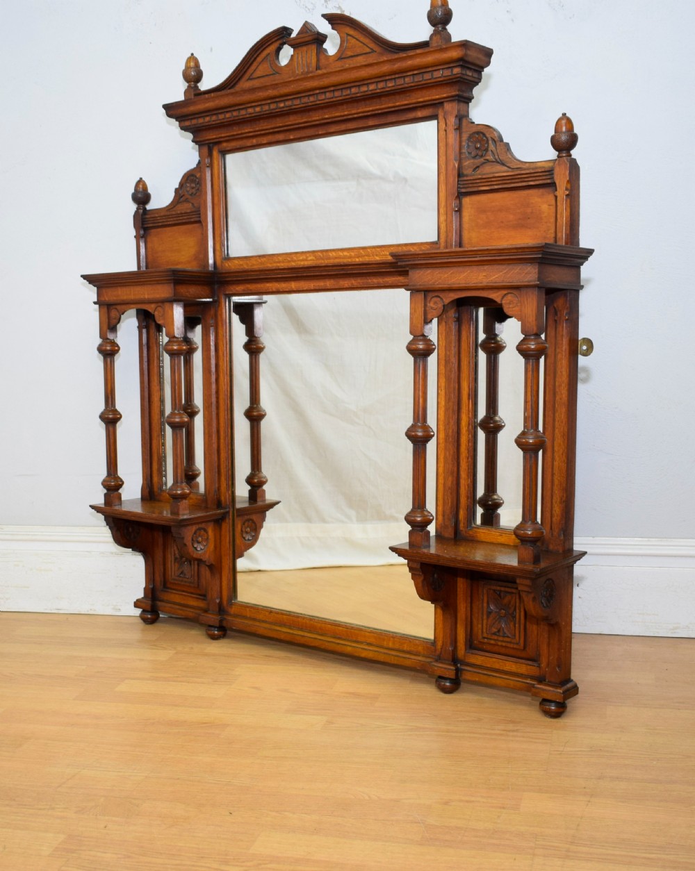 A Victorian carved oak overmantel mirror featuring turned side columns, small side display shelves, an arched pediment, and mirrored glass panels. View XIII