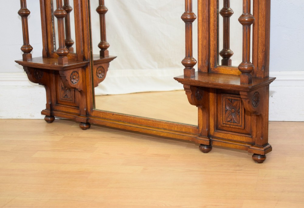 A Victorian carved oak overmantel mirror featuring turned side columns, small side display shelves, an arched pediment, and mirrored glass panels. View XIV