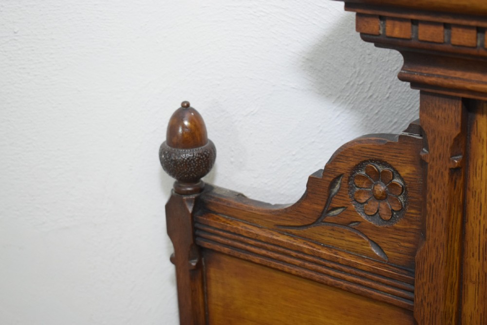 A Victorian carved oak overmantel mirror featuring turned side columns, small side display shelves, an arched pediment, and mirrored glass panels. View XX