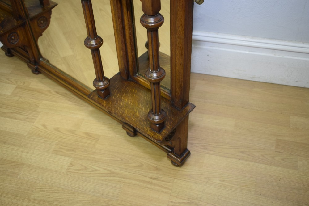 A Victorian carved oak overmantel mirror featuring turned side columns, small side display shelves, an arched pediment, and mirrored glass panels. View XXV