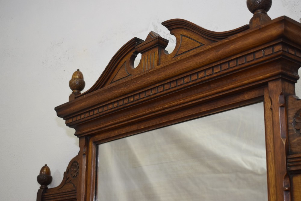 A Victorian carved oak overmantel mirror featuring turned side columns, small side display shelves, an arched pediment, and mirrored glass panels. View XXVI