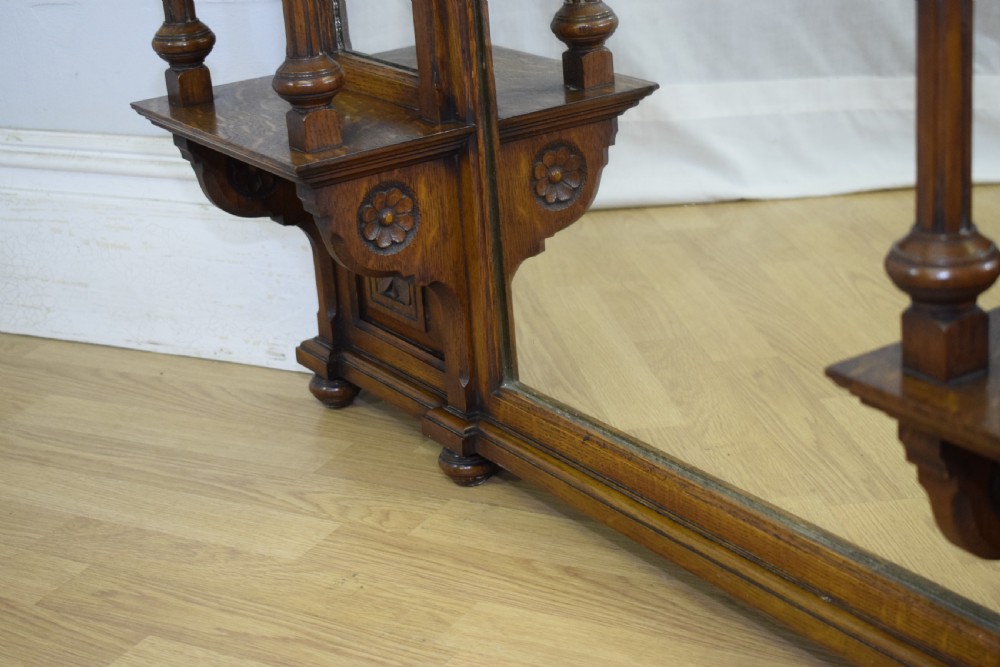 A Victorian carved oak overmantel mirror featuring turned side columns, small side display shelves, an arched pediment, and mirrored glass panels. View XXVIII