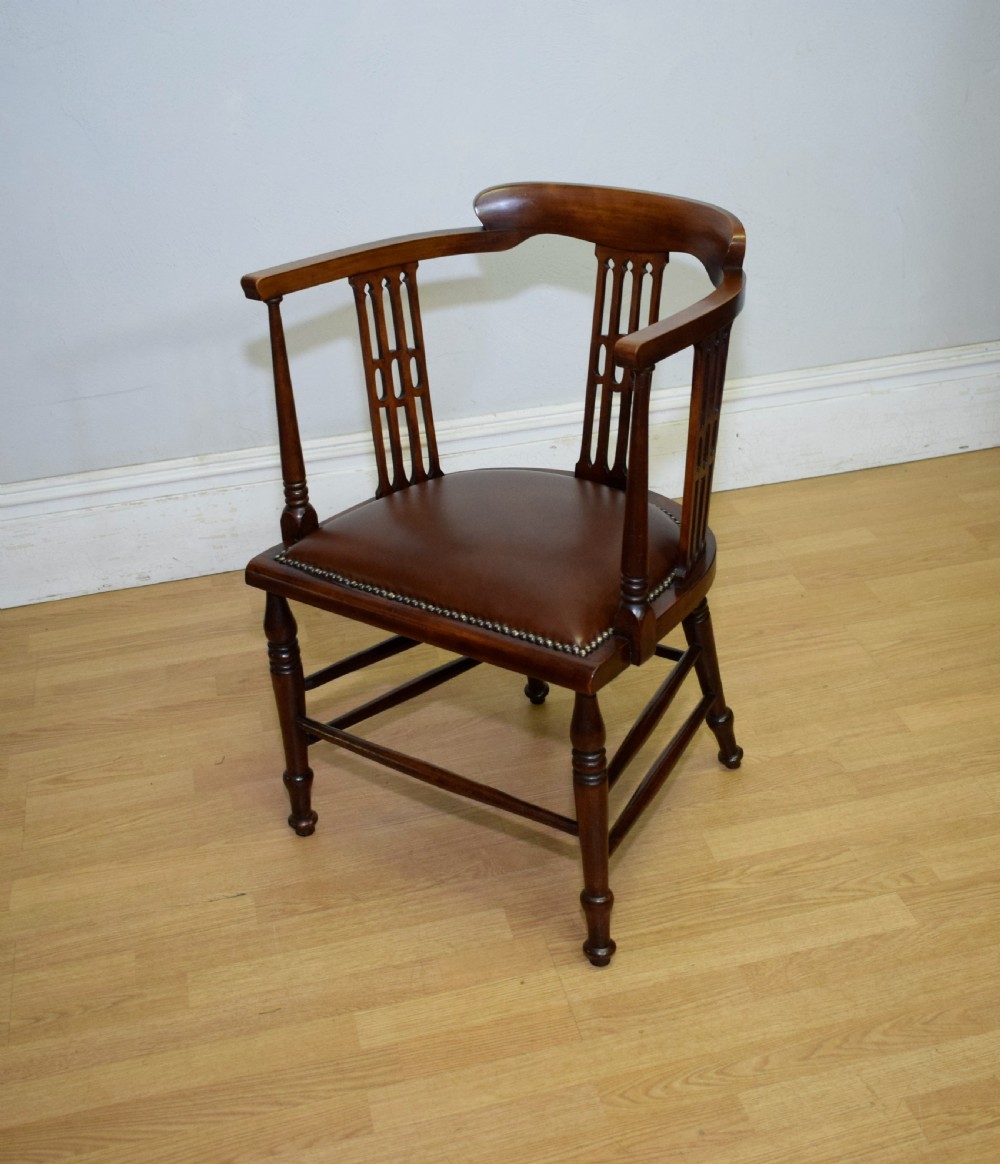 A Victorian dark mahogany tub armchair featuring a curved backrest with pierced vertical splats and a brown leather padded seat secured with brass studs.