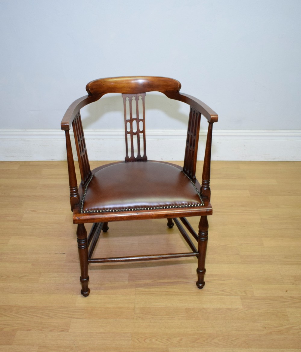 A Victorian dark mahogany tub armchair featuring a curved backrest with pierced vertical splats and a brown leather padded seat secured with brass studs. View II