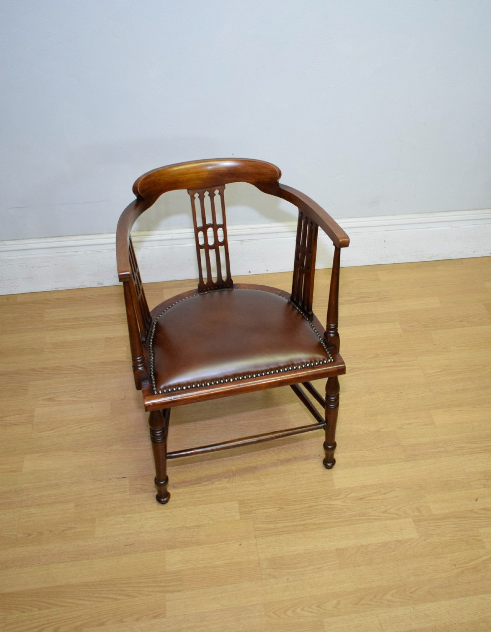 A Victorian dark mahogany tub armchair featuring a curved backrest with pierced vertical splats and a brown leather padded seat secured with brass studs. View III