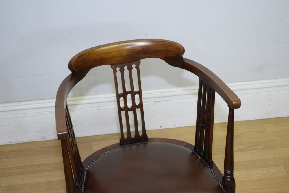A Victorian dark mahogany tub armchair featuring a curved backrest with pierced vertical splats and a brown leather padded seat secured with brass studs. View V