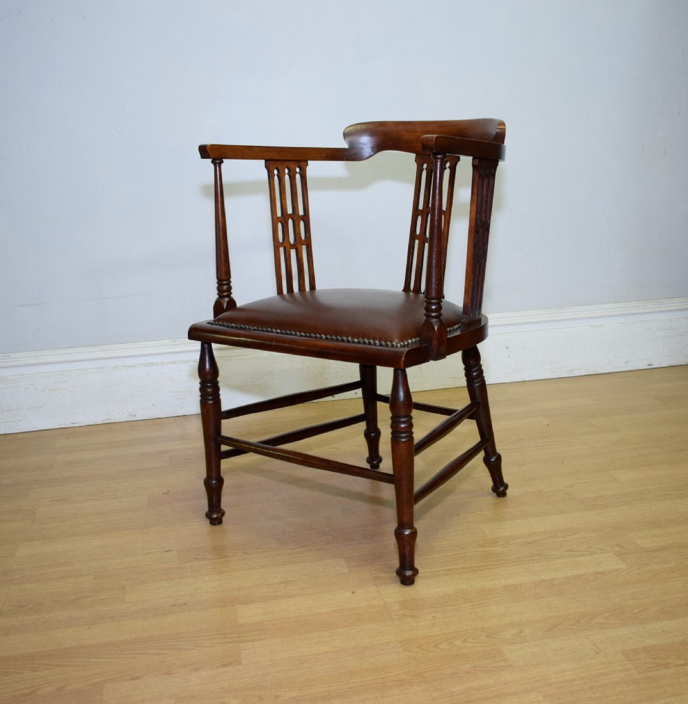 A Victorian dark mahogany tub armchair featuring a curved backrest with pierced vertical splats and a brown leather padded seat secured with brass studs. View VI