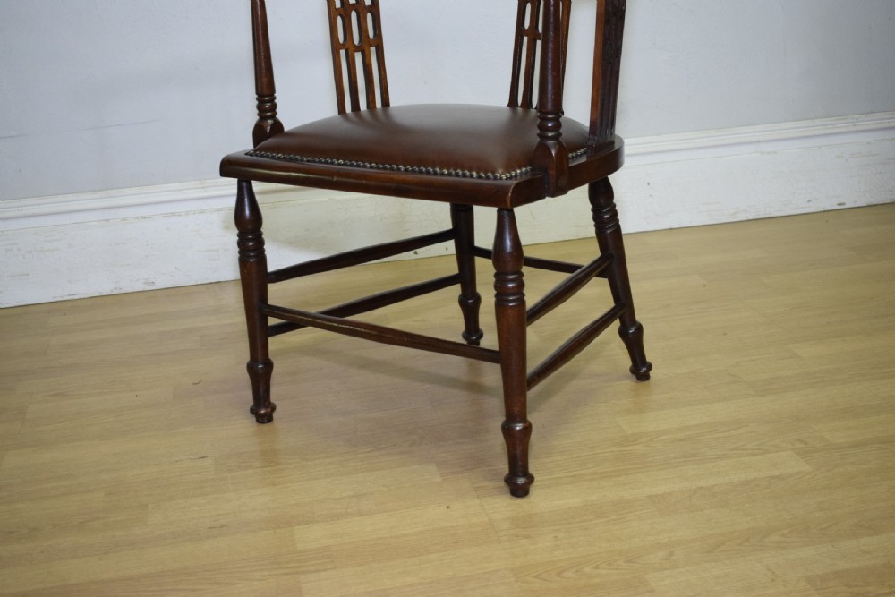 A Victorian dark mahogany tub armchair featuring a curved backrest with pierced vertical splats and a brown leather padded seat secured with brass studs. View VII