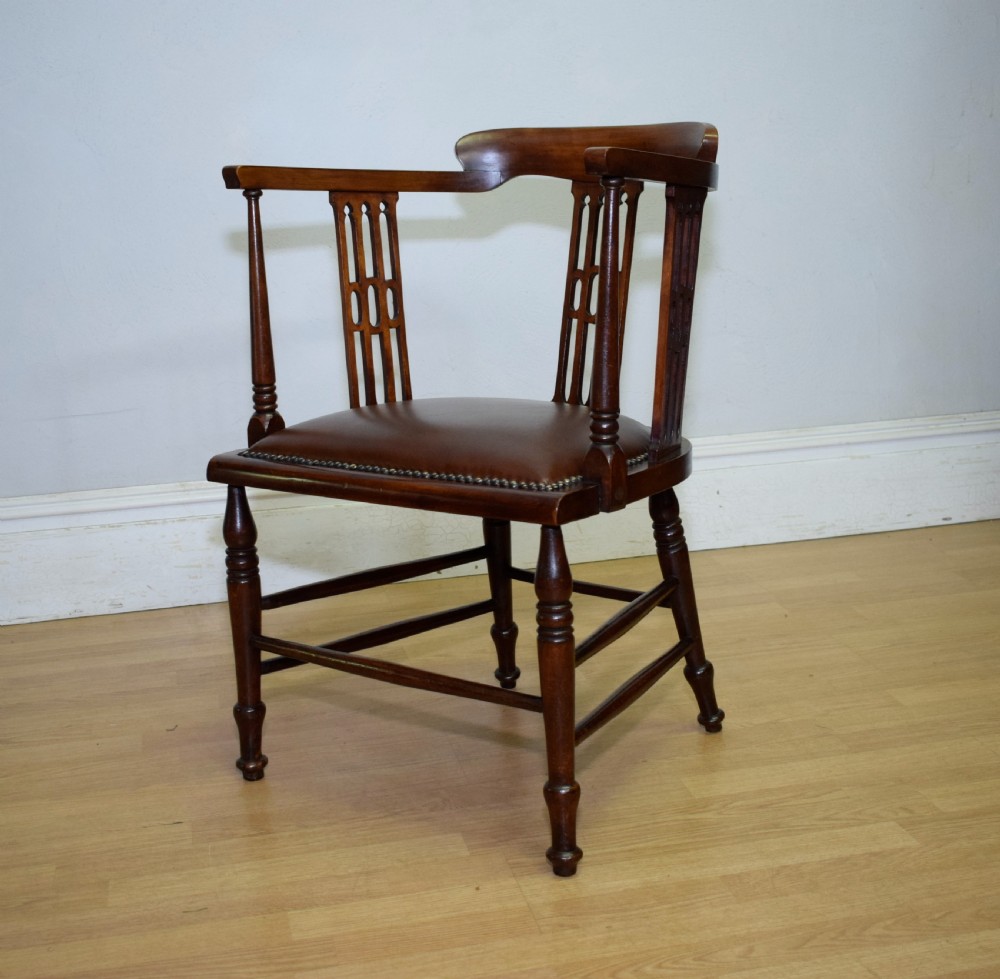 A Victorian dark mahogany tub armchair featuring a curved backrest with pierced vertical splats and a brown leather padded seat secured with brass studs. View VIII