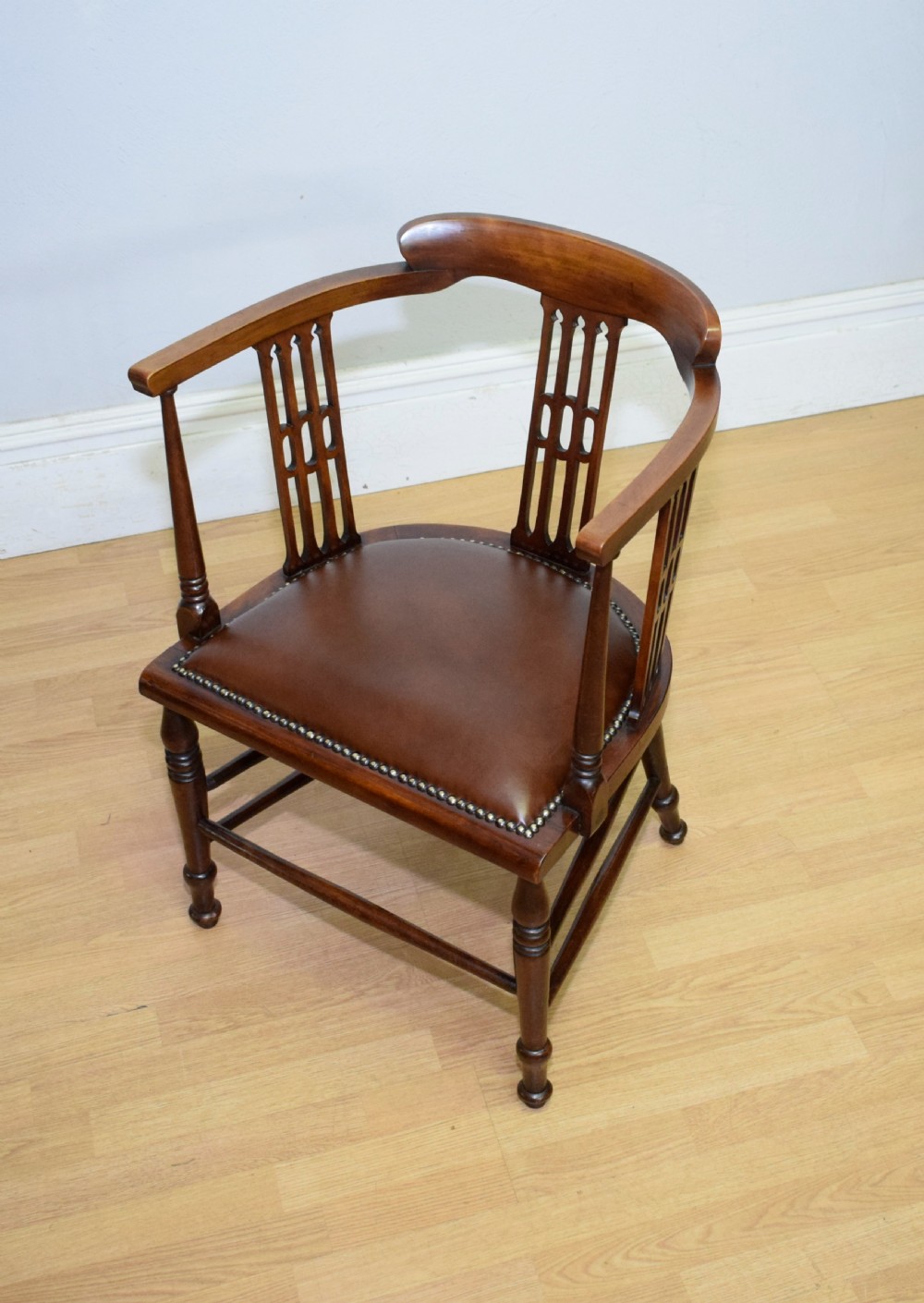 A Victorian dark mahogany tub armchair featuring a curved backrest with pierced vertical splats and a brown leather padded seat secured with brass studs. View IX