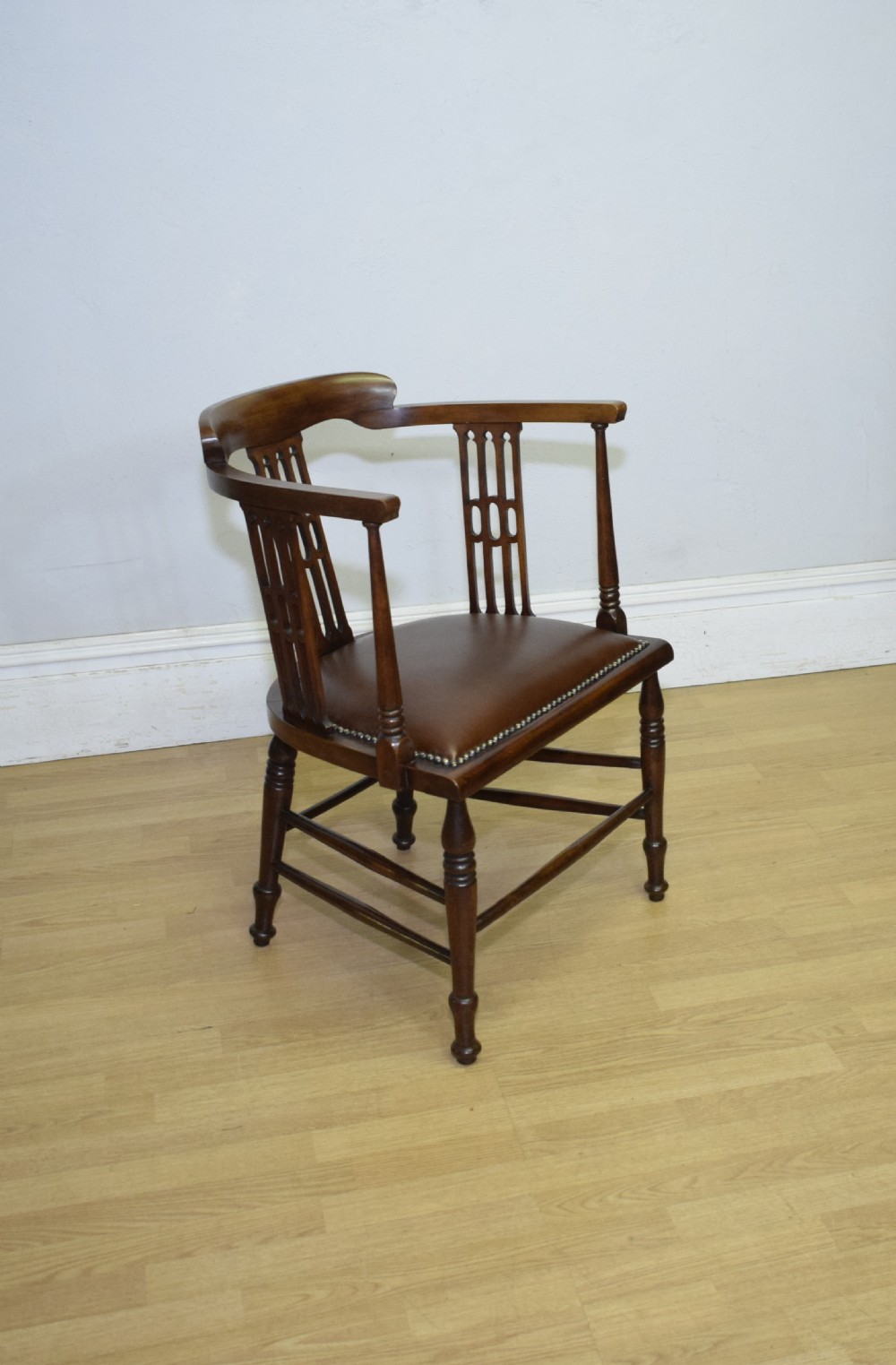 A Victorian dark mahogany tub armchair featuring a curved backrest with pierced vertical splats and a brown leather padded seat secured with brass studs. View XI