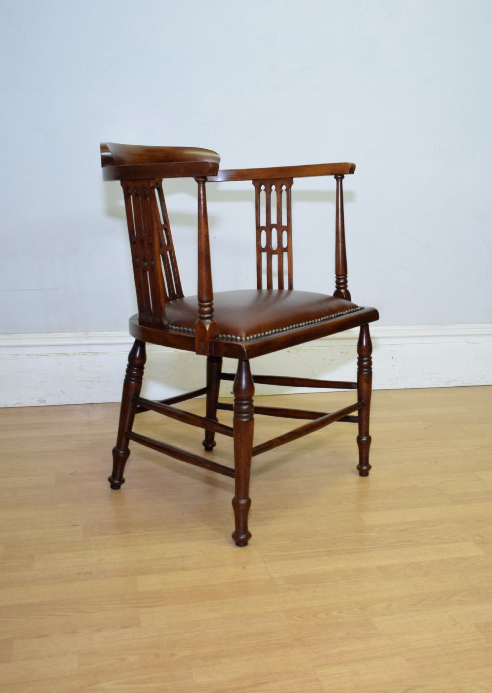 A Victorian dark mahogany tub armchair featuring a curved backrest with pierced vertical splats and a brown leather padded seat secured with brass studs. View XII