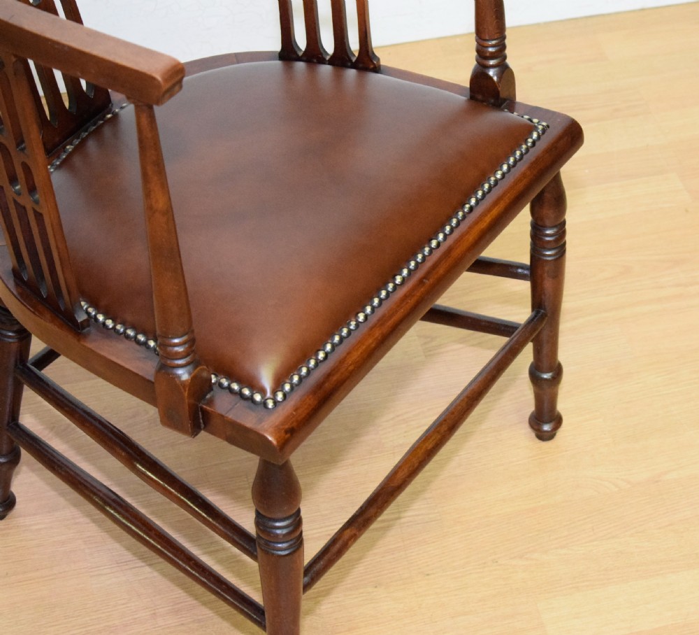 A Victorian dark mahogany tub armchair featuring a curved backrest with pierced vertical splats and a brown leather padded seat secured with brass studs. View XIV