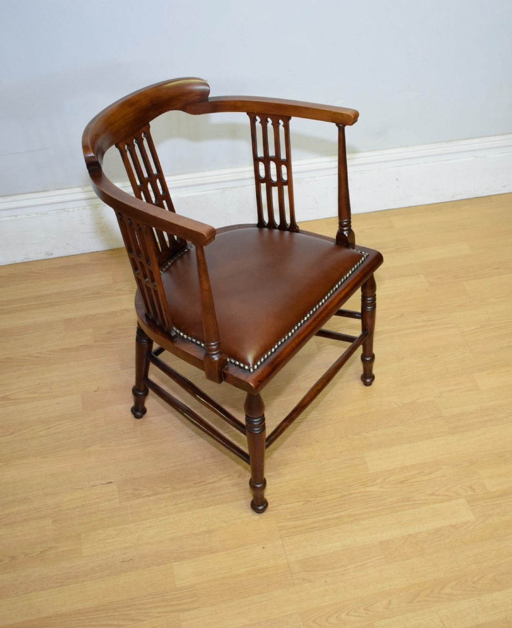 A Victorian dark mahogany tub armchair featuring a curved backrest with pierced vertical splats and a brown leather padded seat secured with brass studs. View XV