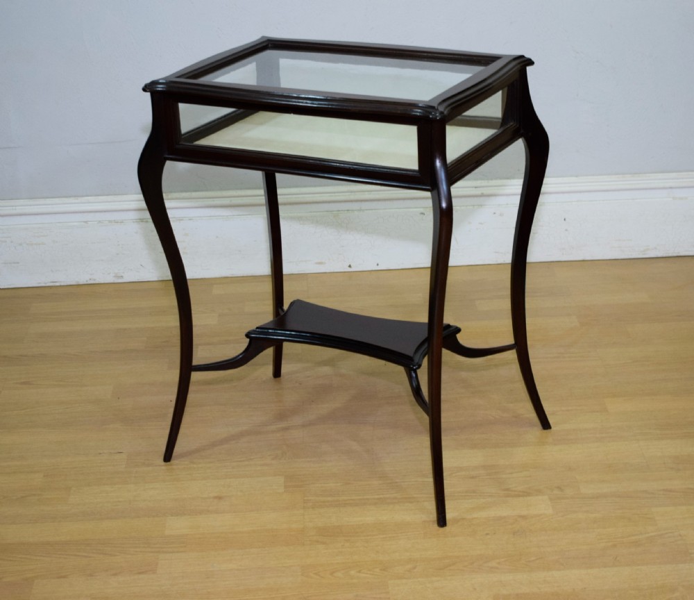 A Victorian dark mahogany bijouterie display table featuring four cabriole legs, clear glass side panels, a hinged glazed top, and a lower curved shelf. View V