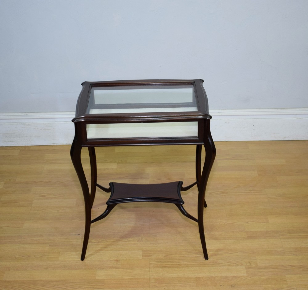 A Victorian dark mahogany bijouterie display table featuring four cabriole legs, clear glass side panels, a hinged glazed top, and a lower curved shelf. View VII