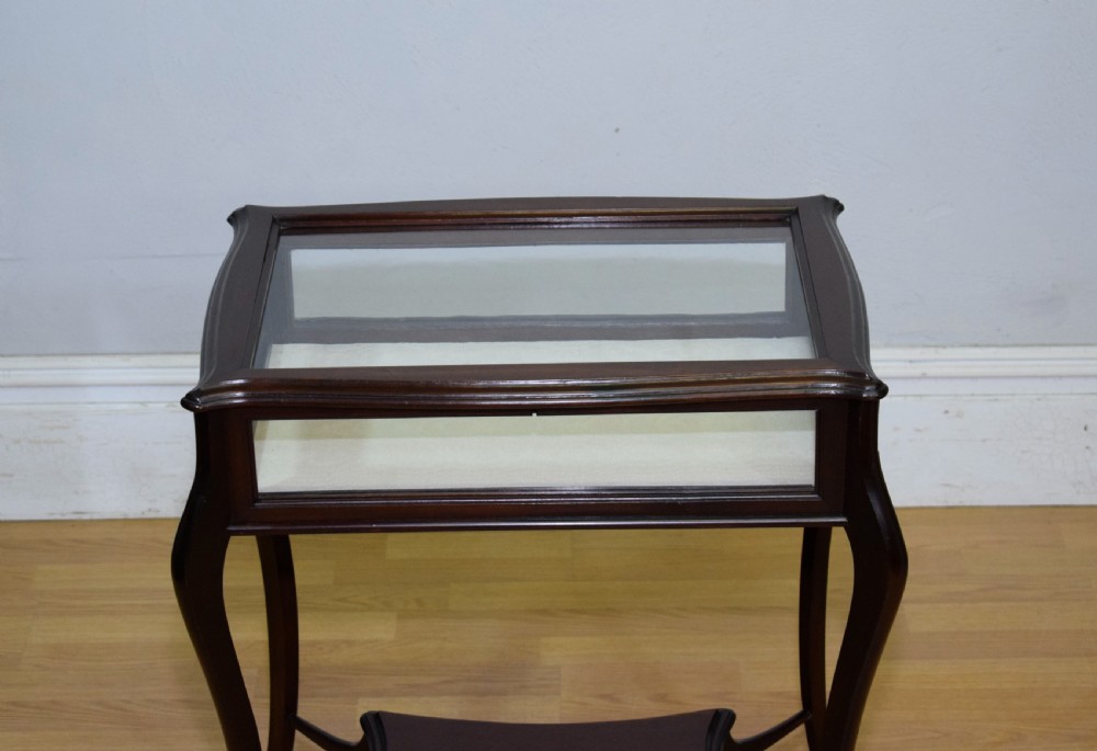 A Victorian dark mahogany bijouterie display table featuring four cabriole legs, clear glass side panels, a hinged glazed top, and a lower curved shelf. View VIII