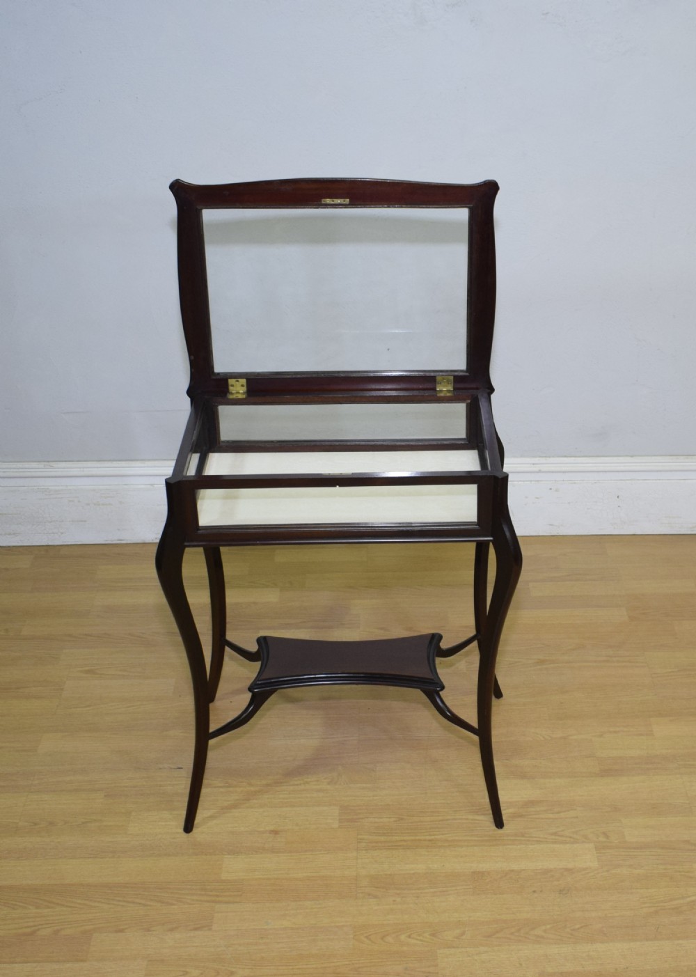 A Victorian dark mahogany bijouterie display table featuring four cabriole legs, clear glass side panels, a hinged glazed top, and a lower curved shelf. View IX