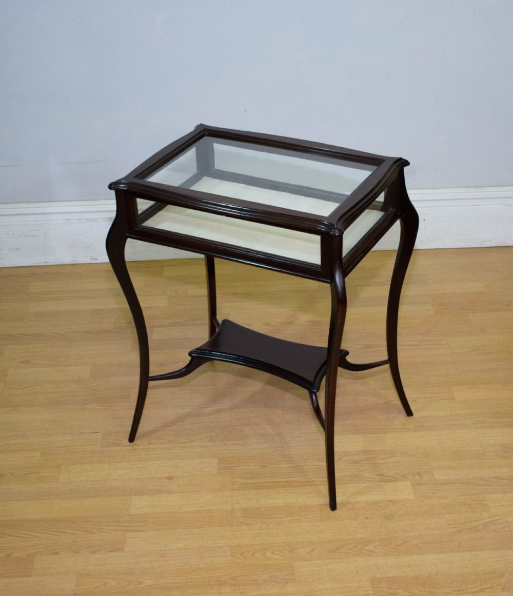 A Victorian dark mahogany bijouterie display table featuring four cabriole legs, clear glass side panels, a hinged glazed top, and a lower curved shelf. View XI