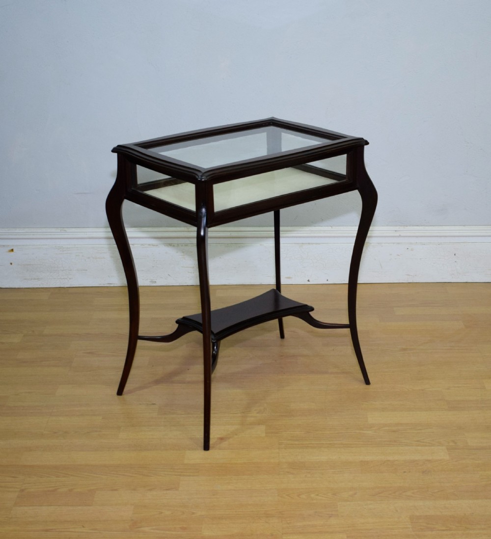 A Victorian dark mahogany bijouterie display table featuring four cabriole legs, clear glass side panels, a hinged glazed top, and a lower curved shelf. View XII